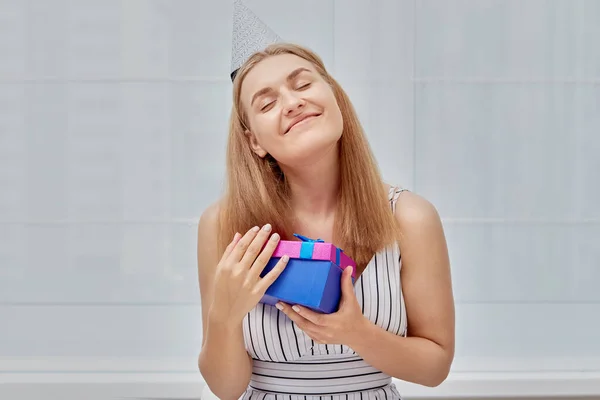 Feliz sonrisa hermosa chica sosteniendo un regalo en una caja brillante en su mano. —  Fotos de Stock