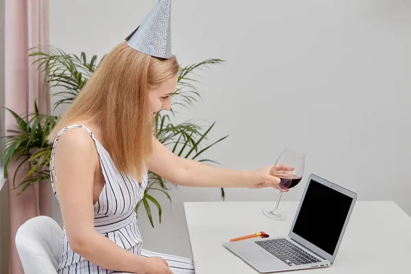 Flicka framför en bärbar dator med en webkamera och ett glas rött vin. — Stockfoto