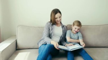 Genç bir ebeveyn evdeki çocuğa koltukta otururken öğretir. 4k