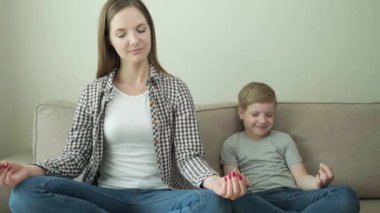 Anne ve çocuk evde kanepede otururken birlikte yoga yapıyorlar. 4k