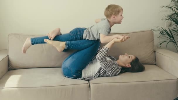 Anne ve oğul eğleniyor, oynuyor ve kanepede eğleniyorlar. İç mimari. — Stok video