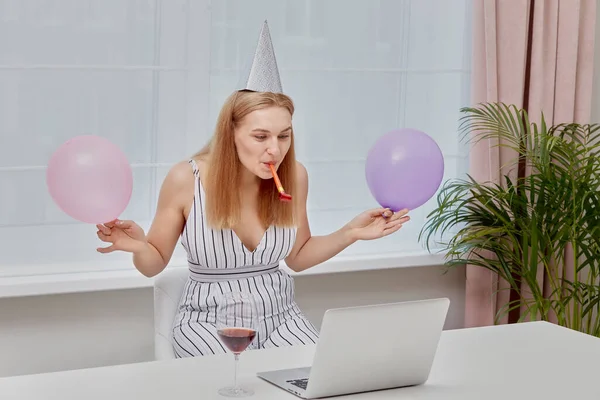 Felice ragazza bionda con bicchieri di vino festeggia un compleanno davanti al computer portatile. — Foto Stock