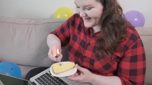 Una hermosa joven enciende velas en un pastel de cumpleaños y pide un deseo. — Vídeos de Stock