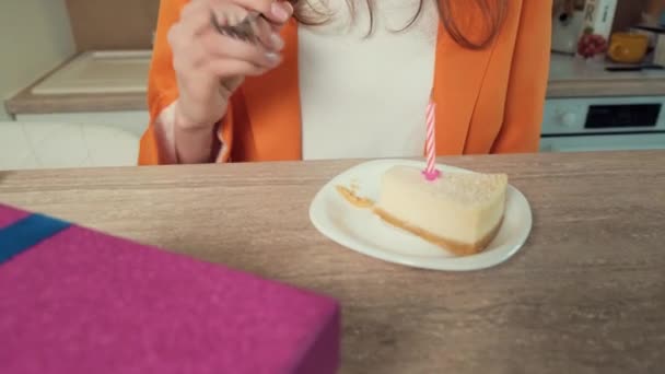 На столе лежит кусок торта. Девушка с удовольствием ест десерт. — стоковое видео