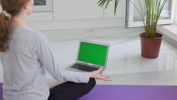 Kvinna yoga hemma. Hon lär sig nya övningar genom att titta på laptopen. — Stockvideo