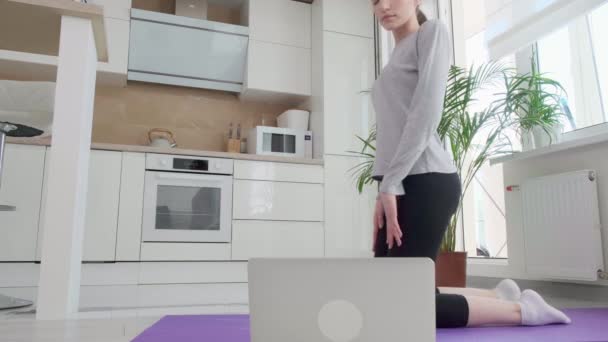 Uma mulher de esportes liga uma lição de treinamento em um laptop. Exercite a prancha. — Vídeo de Stock