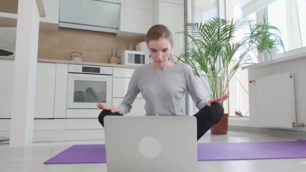 Una joven observa una lección de entrenamiento en un portátil y practica yoga. — Vídeos de Stock