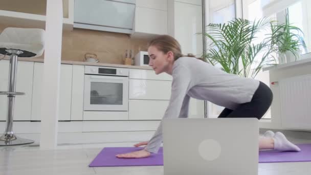 Eine Sportlerin schaltet am Laptop eine Trainingsstunde ein. Übung mit der Planke. — Stockvideo