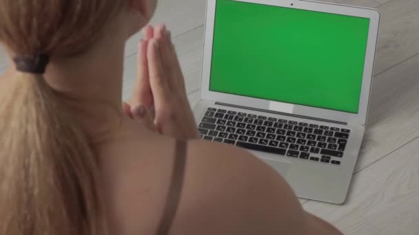 Vista desde atrás. Joven mujer rubia estudia online en casa y practica yoga — Vídeos de Stock