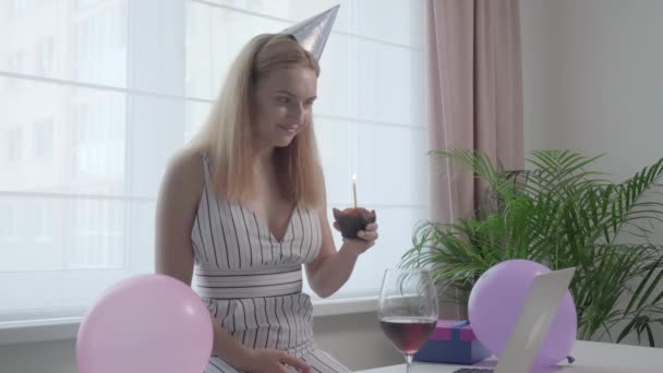 Ευτυχισμένη, χαρούμενη γυναίκα που κρατάει ένα εορταστικό κεκάκι με ένα κερί στα χέρια της. — Αρχείο Βίντεο
