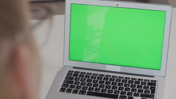 Cierre la computadora portátil en la mesa con pantalla verde en blanco, mesa blanca. — Vídeo de stock