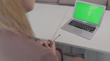 Masada yeşil ekranlı bir laptop var. Reklam için bir yer..