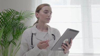 Doktor elinde bir tablet tutuyor ve hastaya reçete yazıyor..