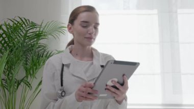 Genç bir doktor elinde bir tablet tutuyor ve hastayı sorguluyor..