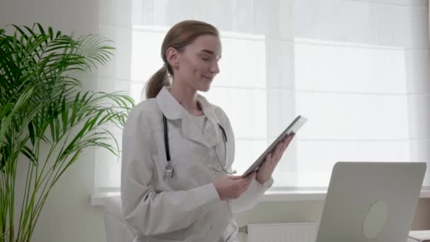 Женщина-врач в медицинском халате консультирует клиента, пациента онлайн. 4k видео. — стоковое видео