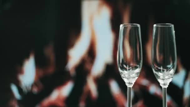 Two glasses stand on the table, against the background of the fireplace. — Stock Video