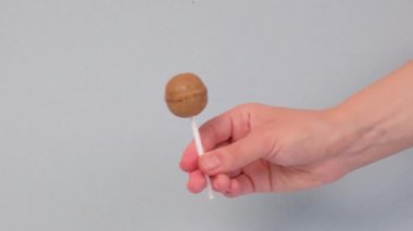 El bir lolipop tutar, karamel bir çubuğun etrafında döner ve onu çevirir..