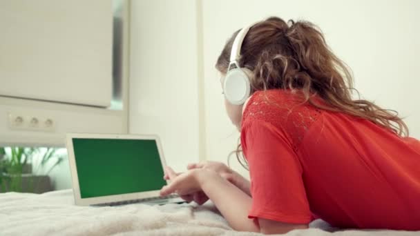 Schoolmeisje meisje draaide zijn rug naar ons, kijkt in het scherm van de laptop. — Stockvideo