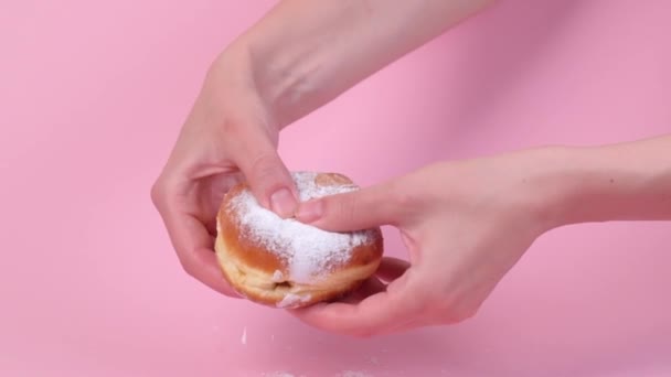 Hands tear open a fresh round stuffed donut. Condensed milk is pouring inside. — Stock Video