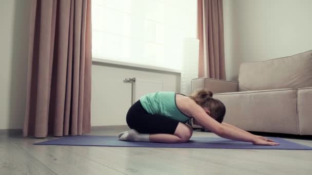 La chica se estira en la alfombra de la sala de estar. Deportes en casa. Cuerpo atlético. — Vídeo de stock