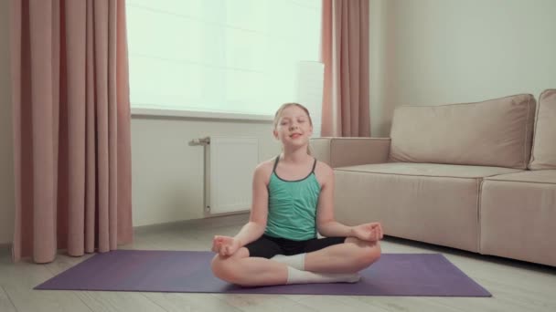 Ein Mädchen praktiziert Yoga zu Hause auf dem Teppich. Einrichtungsgegenstände. Sport zu Hause. — Stockvideo