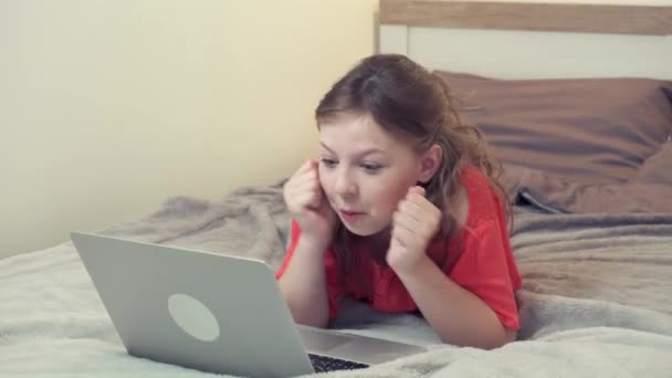 Flickan som ligger på sängen välkomnar tittar in i en bärbar dator bildskärm. Utbildning på nätet. — Stockvideo