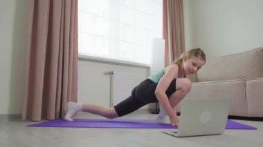 Salgın sırasında evde egzersiz yapmak için. Kız bir video dersi izliyor..