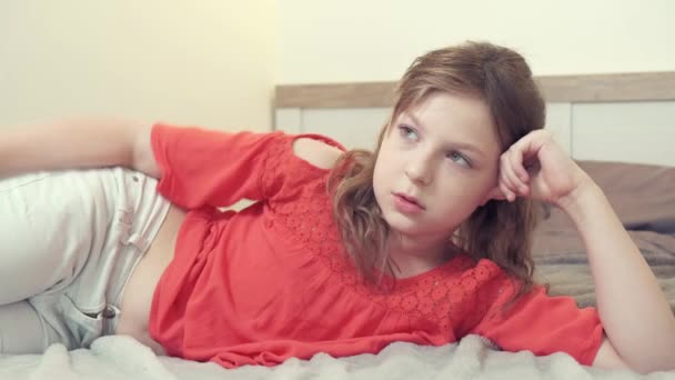Красива брюнетка дівчина говорить до камери, лежачи на ліжку вдома . — стокове відео