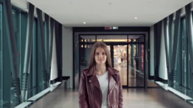 Bir kız sokakta yürüyor, arka planda bir alışveriş merkezinin kapısında..