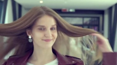 Genç bir kadın güzel, uzun saçlarını düzleştirir ve ileri doğru yürür..