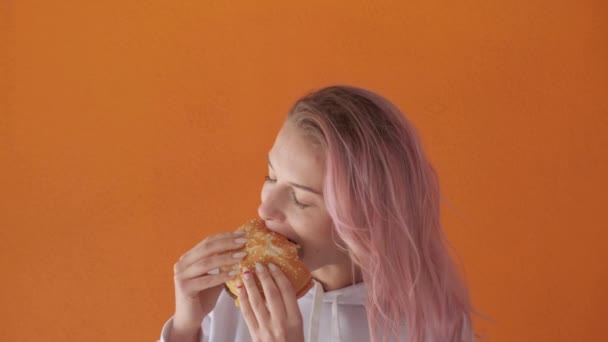 Kız fast food yiyor. İştahlı bir kadın büyük lezzetli bir burger yemek istiyor.. — Stok video