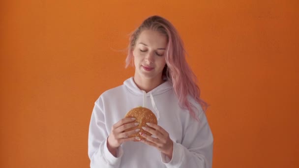 Mulher jovem com apetite para comer hambúrguer saboroso grande. Gozo de comida. — Vídeo de Stock