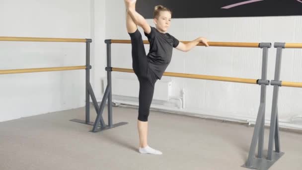 Un joven bailando ballet profesionalmente, un chico rubio estira la pierna. — Vídeo de stock
