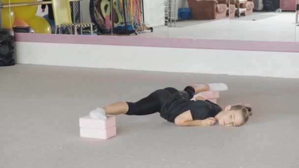Красивый молодой парень лежит на полу и делает упражнения на растяжку. — стоковое видео
