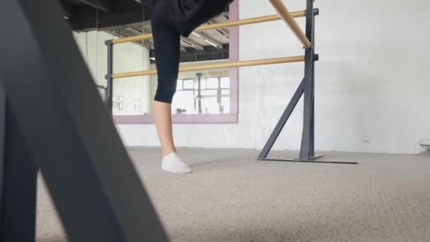 Effectue des exercices de ballet, jambe en arrière. Cours de danse. Jambes rapprochées. — Video