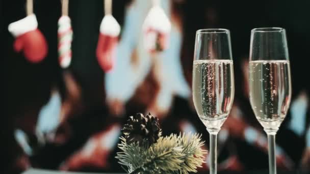 Bolhas de champanhe em dois copos altos. Uma lareira queima no fundo. — Vídeo de Stock
