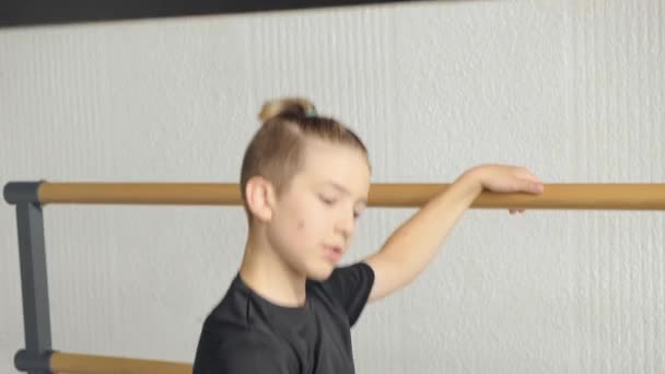 The boy is dancing ballet, one hand on the barre, the other to the side. — Stock Video