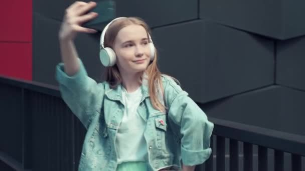 美しいブロンドの女の子は音楽に耳を傾け、スマートフォンで自画自賛. — ストック動画