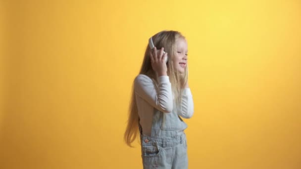 Gyönyörű fiatal szőke lány fülhallgatóval zenét hallgatni és táncolni. — Stock videók