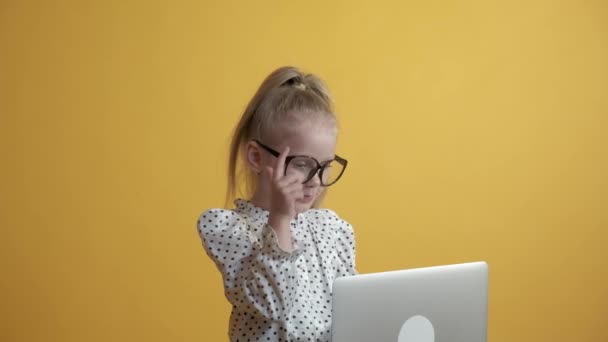 Het blonde meisje kijkt aandachtig naar het laptopscherm. Terug naar school. — Stockvideo