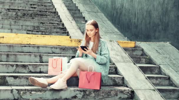 Ένα κορίτσι που κάθεται στις σκάλες του δρόμου επικοινωνεί στα κοινωνικά δίκτυα.. — Αρχείο Βίντεο