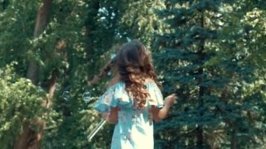 Uzun saçlı güzel bir kız daireler çiziyor ve kabarcıklar çıkarıyor..