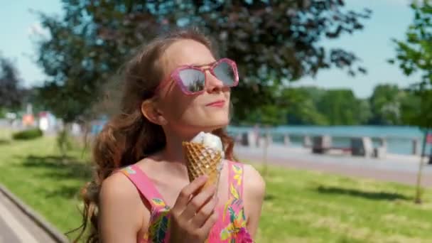 Gelukkig meisje in zonnebril eten ijs en genieten van het zonnige weer. — Stockvideo