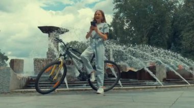 Uzun saçlı bir kız fıskiyenin arkasında selfie çekiyor..