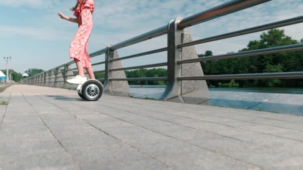Flickan åker en gyro scooter i en cirkel. För att hålla balansen. Långsamma rörelser. — Stockvideo