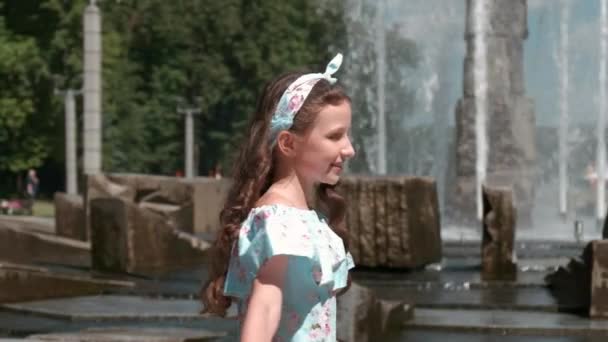 A beautiful girl in a full-length dress near the fountain. Long beautiful hair. — Stock Video