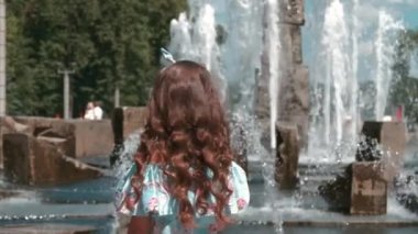 Çeşmenin yanında uzun elbiseli bir kız. Elindeki çubukta şeker.