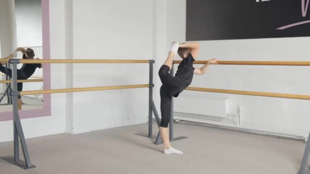 Een jongeman die ballet doet, steekt zijn been omhoog. Flexibele slanke body — Stockvideo