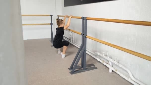 The young guy performs the plie pose exercise. Hands on the barre. Legs in socks — Stock Video