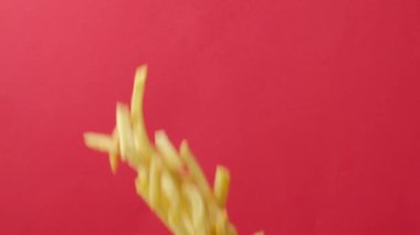 Pembe arka planda havada patates kızartması uçuşuyor. Kızartmalar düşüyor, uçuyor.